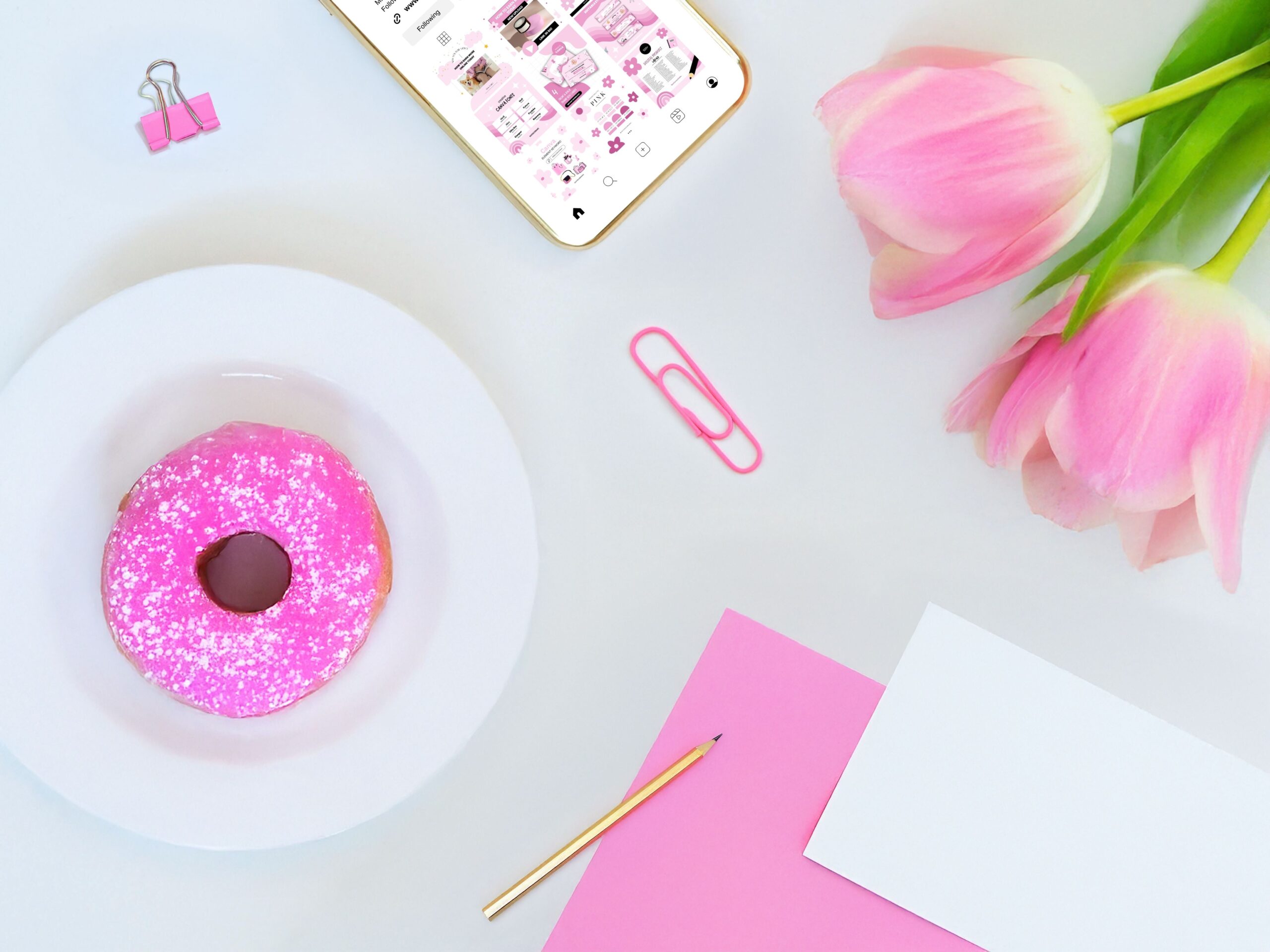 Pink tulips, gold pen, pink notebook, donut on plate, pink clips, and gold smartphone mockup.