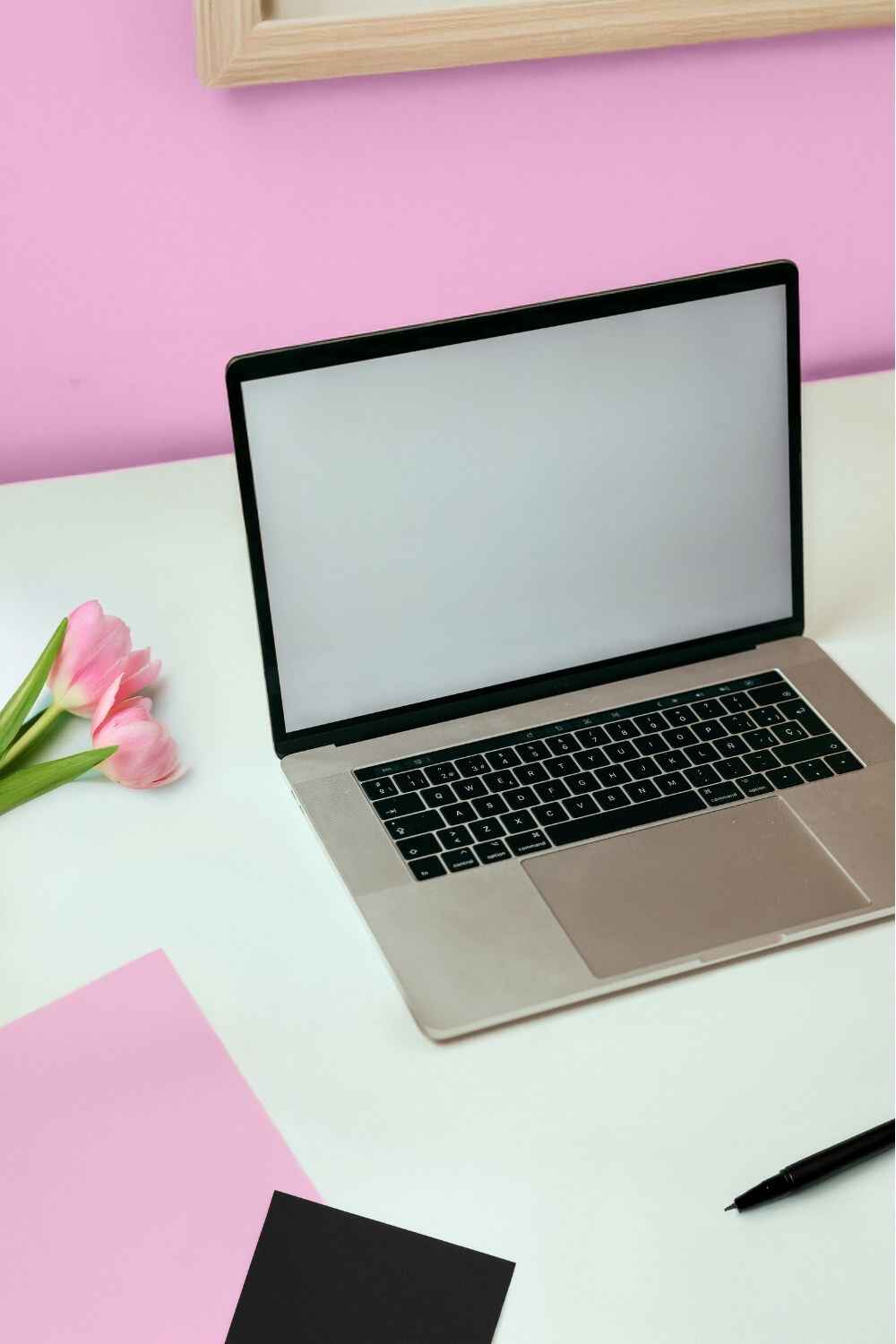 Laptop on white desk with pink tulips — How to Start Selling Digital Products as a Beginner blog.
