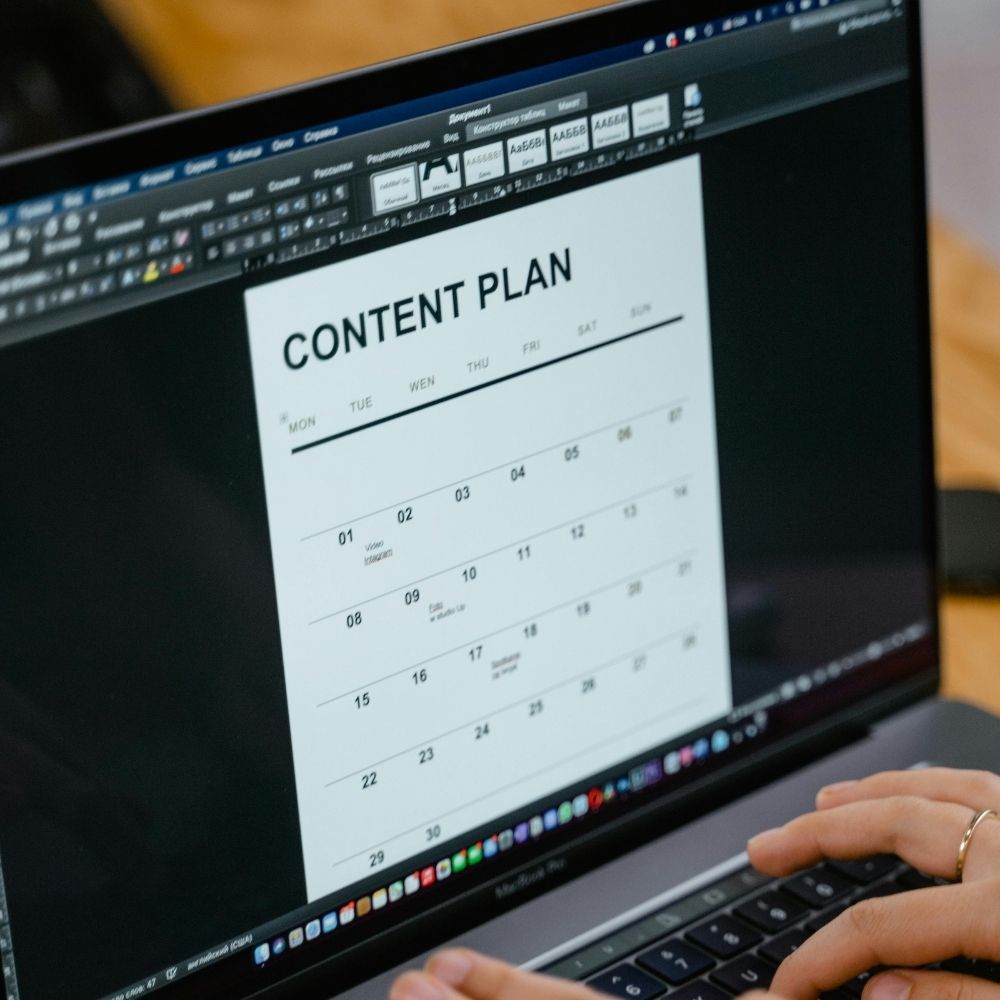 Person using a laptop with a content plan calendar template open.