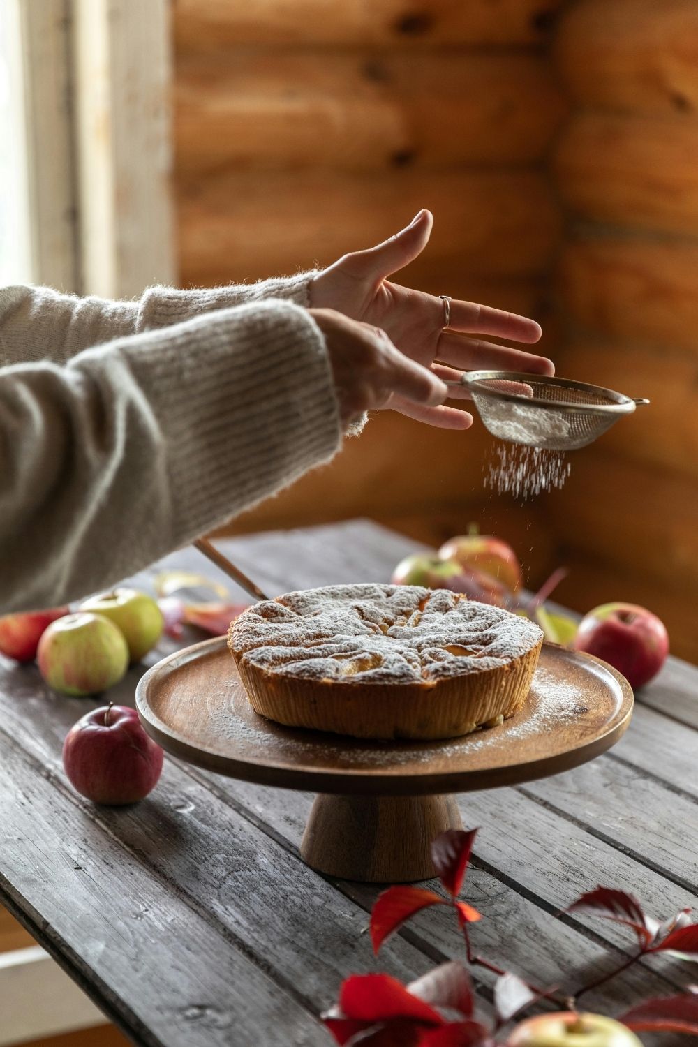 A woman finishing an apple pie, surrounded by fresh apples.